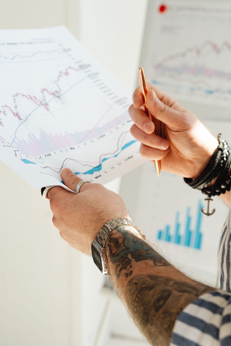 Person holding a pen over printed charts